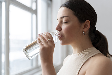 Mujer activa con botella de agua, priorizando la hidratación durante los días calurosos