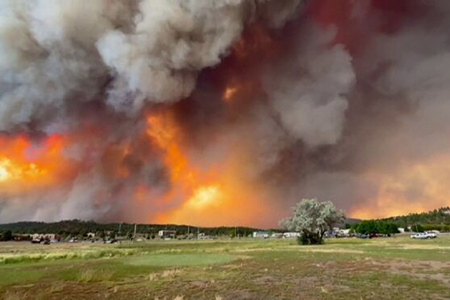 Una densa pared de humo cubre el cielo de Ruidoso mientras vehículos evacúan la zona debido a los incendios en tierras Apache Mescalero. Miles de residentes han sido evacuados por la rápida propagación de los incendios South Fork y Salt Fire.