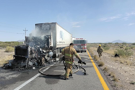 Personal de Protección Civil Ahumada y Bomberos trabajando para extinguir el incendio en la cabina de un tractocamión en la carretera Juárez-Ahumada.