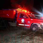 Camión de bomberos estacionado en la calle mientras los bomberos trabajan para apagar el incendio en el ejido Benito Juárez.