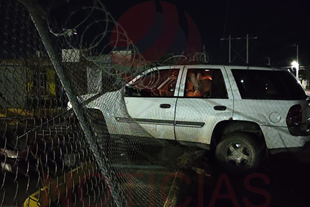 Vehículo blanco estrellado contra el cerco de la maquiladora Lear en Nuevo Casas Grandes durante la noche.