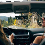 Un automóvil recorriendo una carretera costera, destacando la belleza del paisaje y la libertad de parar a disfrutar de vistas impresionantes.