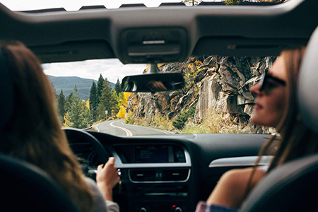 Un automóvil recorriendo una carretera costera, destacando la belleza del paisaje y la libertad de parar a disfrutar de vistas impresionantes.