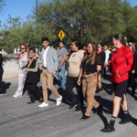 Participantes de la caminata de activación física en Nuevo Casas Grandes recorren la avenida Constitución hacia la Macro Plaza. Autoridades locales, seis instituciones educativas y padres de familia se unieron en esta actividad para promover el bienestar y la salud en la comunidad.