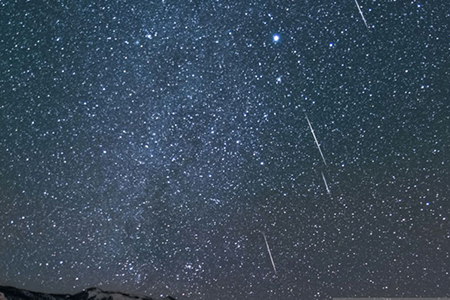 Cielo estrellado iluminado por la lluvia de estrellas Táuridas en México, con meteoros visibles sobre el horizonte en una noche despejada de noviembre.