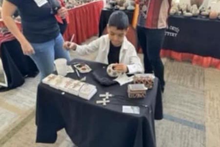 Yetito Gallegos, de 9 años, se prepara para exhibir su cerámica en la Feria Internacional Las Cruces Arts Fair en Nuevo México.